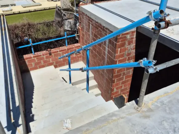 Close-up of a scaffold coupler and edge protection on a brick building corner in Dunsborough