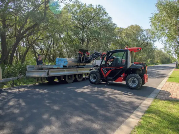 Bay Scaffold telehandler towing a materials trailer through a Dunsborough street