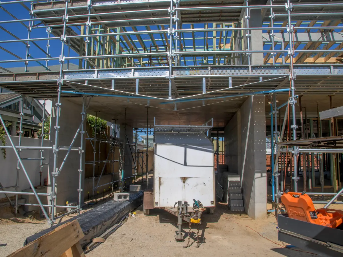 Bridging ledger holding scaffold open over a garage for drive-through access